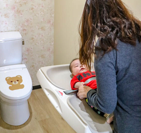 バリアフリーの多目的トイレに案内するスタッフとお子さま