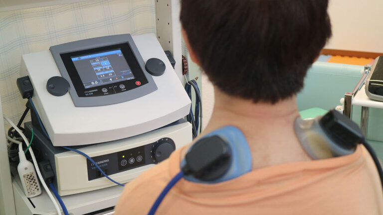 立体動態波治療器で腰痛や交通事故の深部を刺激する施術風景