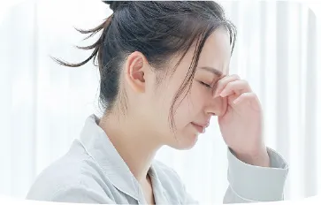 頭痛を訴える女性がこめかみを押さえている様子
