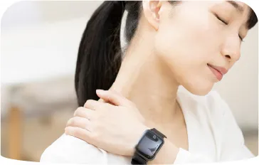 肩を押さえる女性の姿、肩こりや腰痛のケアを連想させる場面
