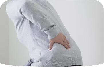 妊婦が腰を手で押さえ腹部を支え痛みを訴える様子